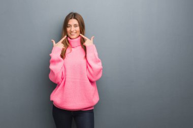 Genç Rus doğal kızı gülümsüyor, ağzını işaret ediyor.