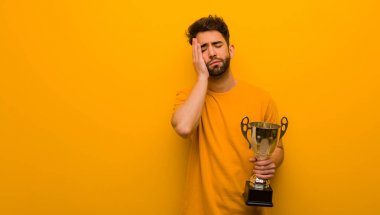 Elinde kupa tutan genç adam yorgun ve çok uykulu.