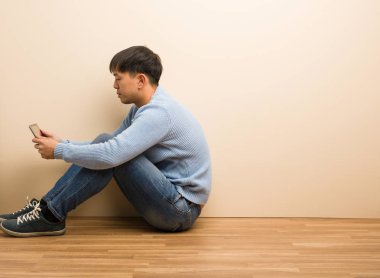 Genç Çinli adam tabletini kullanarak oturuyor ve önüne bakıyor.