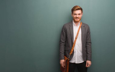 Genç kızıl saçlı iş adamı. Neşeli, büyük bir gülümsemesi olan.