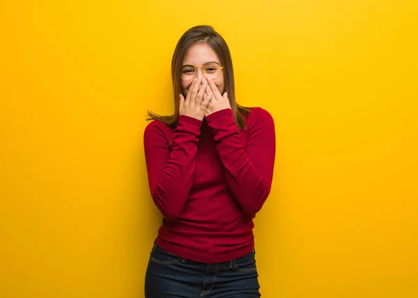 Young intellectual woman laughing about something, covering mouth with hands