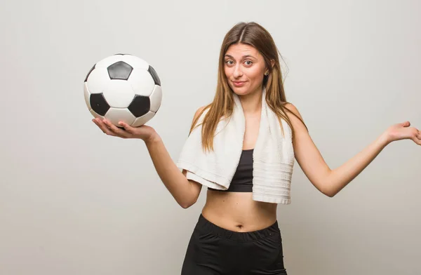 Young Fitness Russian Woman Doubting Shrugging Shoulders Holding Soccer Ball — Stock Photo, Image
