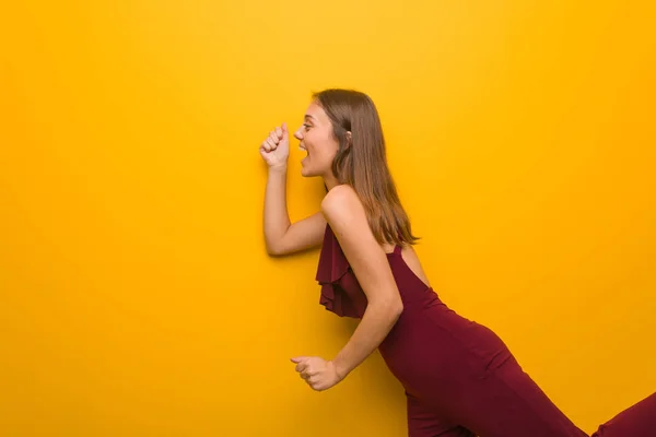 Young natural woman wearing a red dress against an orange wall — Stock Photo, Image