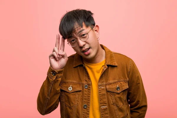 Young chinese man wearing a jacket fun and happy doing a gesture of victory