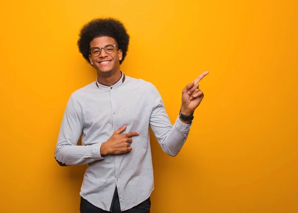 Turuncu Bir Duvarın Üzerinde Parmakla Yan Gösteren Genç Afro Amerikan — Stok fotoğraf