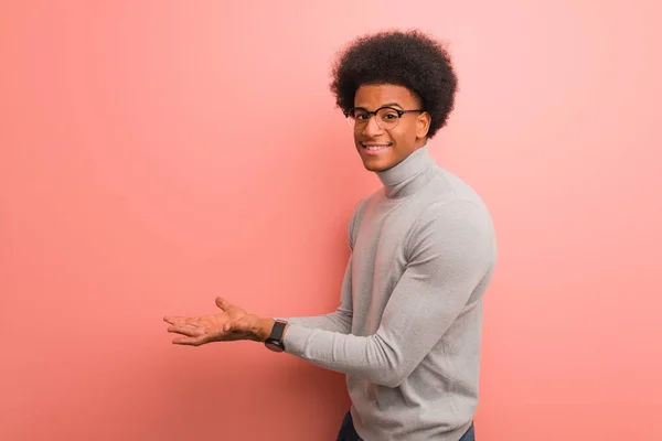 Giovane Uomo Afroamericano Sopra Muro Rosa Che Tiene Qualcosa Con — Foto Stock