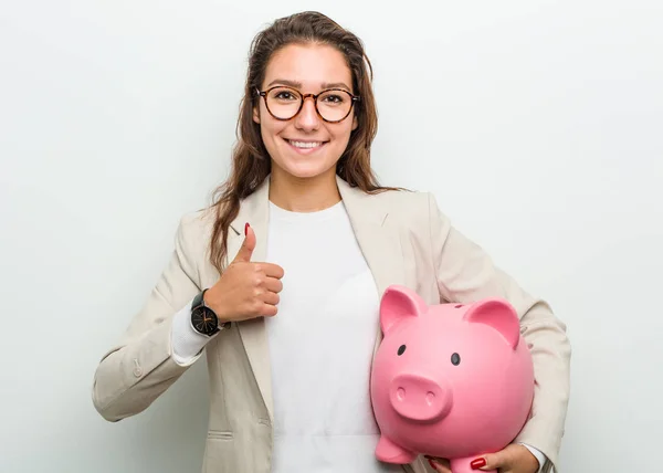 Joven Empresaria Europea Sosteniendo Una Alcancía Sonriendo Levantando Pulgar — Foto de Stock