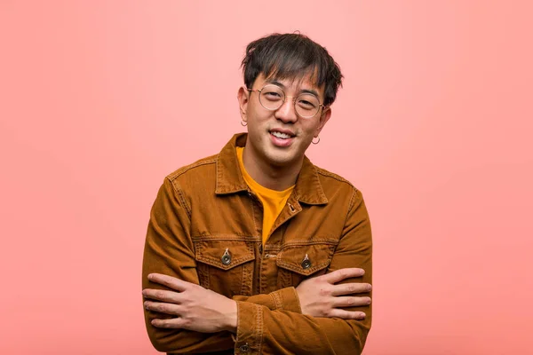 Young chinese man wearing a jacket crossing arms, smiling and relaxed