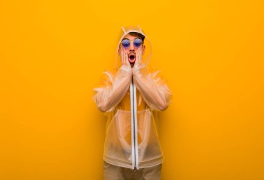 Yağmurluk giyen genç adam şaşırdı ve şok oldu.