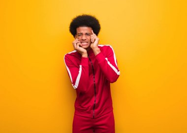 Turuncu bir duvarın üzerinde umutsuz ve üzgün genç bir zenci.