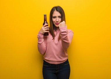 Elinde bira tutan genç ve güzel bir kadın, kızgın bir yüz ifadesi var.