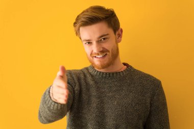 Genç kızıl saçlı adam yakından bakıyor. Birini selamlamak için uzanıyor.