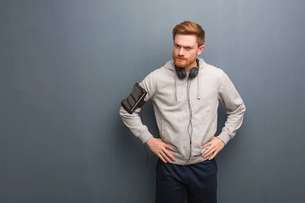 Young fitness redhead man scolding someone very angry