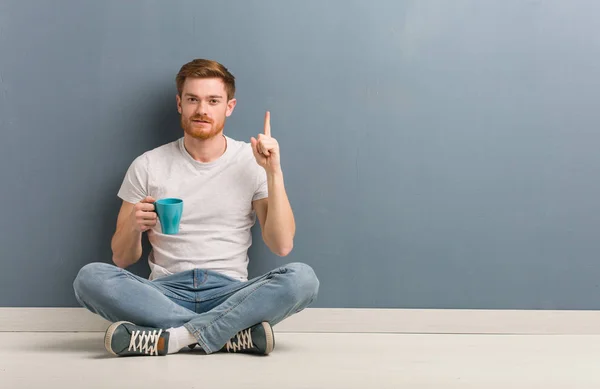 Young Redhead Student Man Sitting Floor Showing Number One Holding — Stock Photo, Image