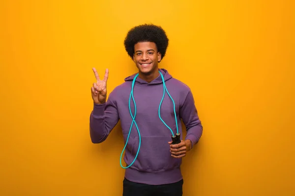 Young african american sport man holding a jump rope fun and happy doing a gesture of victory