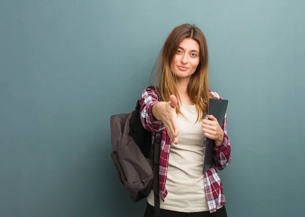 Young student russian woman reaching out to greet someone