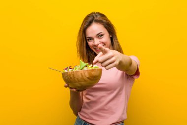 Elinde salata tutan sağlıklı bir kadın. Neşeli gülümsemeler öne bakıyor..