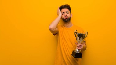 Elinde bir kupa tutan genç adam endişeli ve şaşkın.