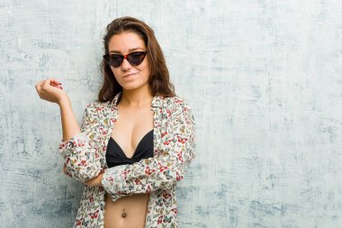 Bikini giyen genç Avrupalı kadın kafasının arkasına dokunuyor, düşünüyor ve bir seçim yapıyor..