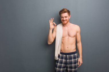 Havluyu tutan genç kızıl saçlı adam neşeli ve kendinden emin, iyi bir jest yapıyor. Elinde beyaz bir havlu var..