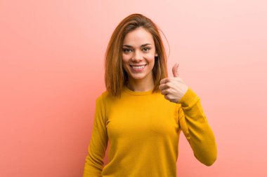 Genç ve güzel bir bayan gülümsüyor ve başparmağını kaldırıyor.