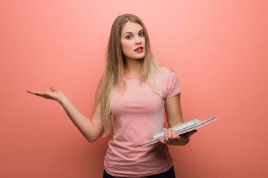 Genç, güzel Rus kız avuç içinde bir şey tutuyor. Elinde kitaplar var..