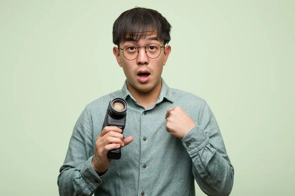 Young Chinese Man Holding Vintage Camera Surprised Feels Successful Prosperous — ストック写真