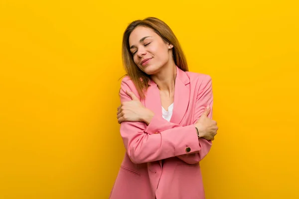 Young fashion business woman hugs herself, smiling carefree and happy.