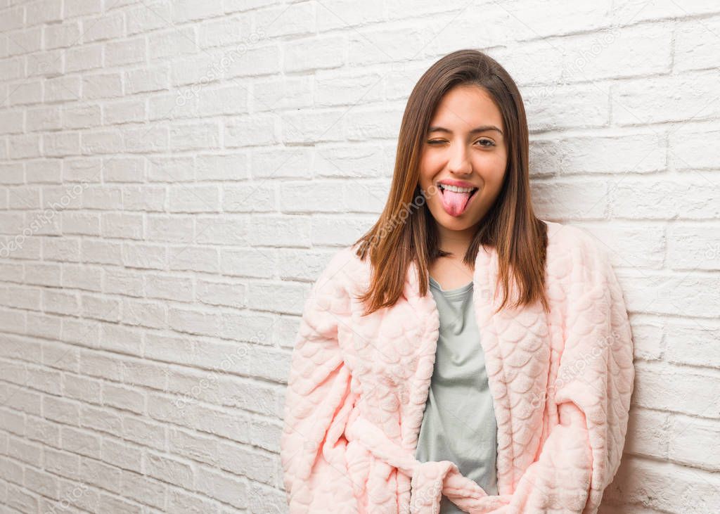 Young woman wearing pajama funnny and friendly showing tongue