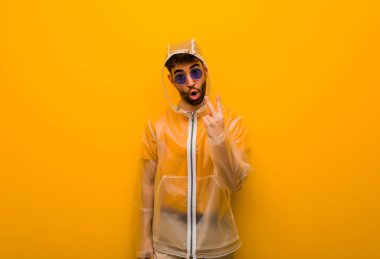 İki numarayı gösteren yağmurluk giyen genç bir adam.