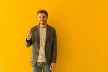 Genç kızıl saçlı iş adamı gülümsüyor ve başparmağını kaldırıyor.