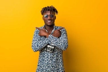 Tatil kıyafeti giyen genç siyah Rasta iki seçenekten birini seçmeye çalışıyor..