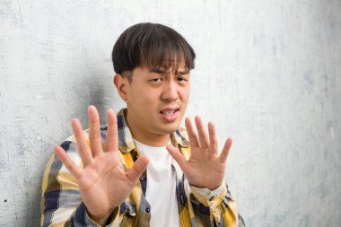 Genç Çinli bir adam, bir şeyi reddederek, tiksinti jesti yaparak yakından bakar.