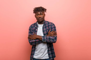 Kendine güveni tam genç Afrikalı bir zenci, kararlılıkla kollarını kavuşturuyor..