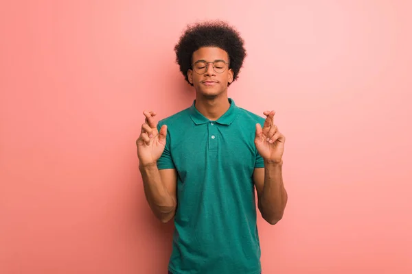 Giovane Uomo Afroamericano Sopra Muro Rosa Incrociando Dita Avere Fortuna — Foto Stock