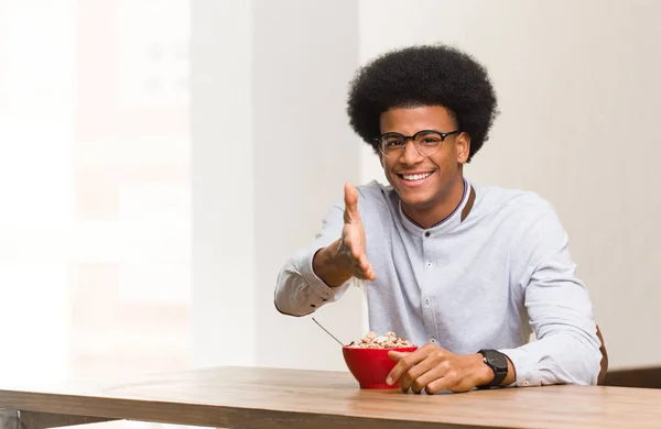 Young black man having a breakfast reaching out to greet someone