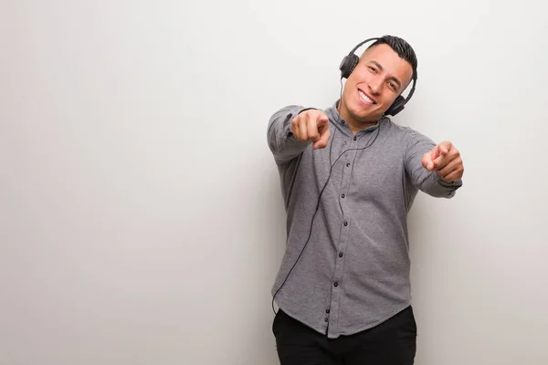 Mladý Latinský Muž Poslouchá Veselou Hudbu Usmívá Ukazuje Dopředu — Stock fotografie