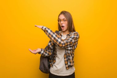 Genç bayan elinde çok şaşırmış ve şok olmuş bir şey tutuyor.