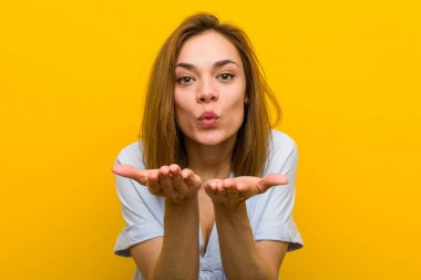 Genç güzel genç kadın dudakları katlanır ve hava öpücük göndermek için avuç içi tutarak.