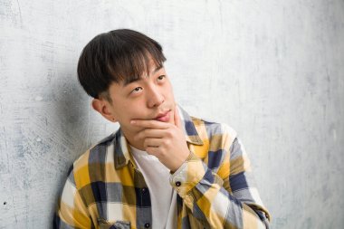 Genç Çinli adamın yüzü şüpheli ve kafası karışmış.