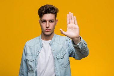 Kotlu tişört giyen genç ve yakışıklı bir öğrenci elini uzatmış, dur işareti göstererek seni engelliyor..