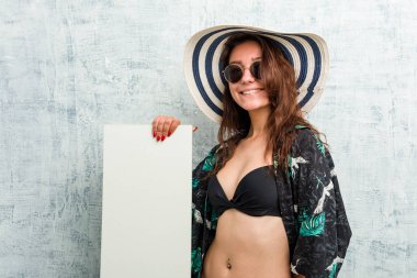 Bikini giyen ve pankart tutan Avrupalı genç bir kadın.