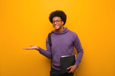 Genç Afrikalı Amerikalı öğrenci avuç içinde bir şey tutuyor.