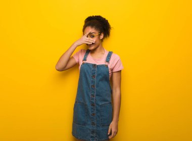 Mavi gözlü genç siyah Afrikalı Amerikalı kız aynı anda utanıyor ve gülüyor