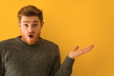 Genç kızıl saçlı adamın yüzü, avucunun içinde bir şey tutuyor.