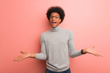 Pembe bir duvar üzerinde genç Afrikalı Amerikalı adam şüphe ve Shrugging omuz