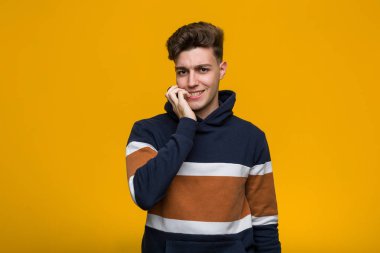 Tırnaklarını yiyen kapüşonlu genç, havalı bir adam. Gergin ve endişeli..