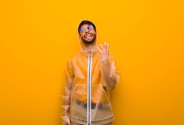 Yağmurluk giyen genç adam çok korkmuş ve korkmuş.