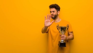 Elinde kupa tutan genç adam elini öne koyuyor.