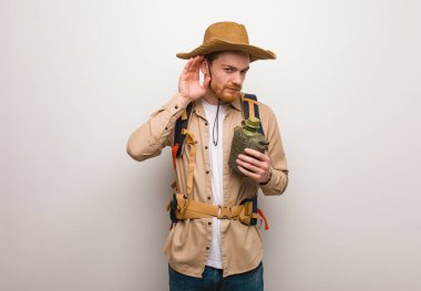 Genç kızıl saçlı kaşif bir dedikoduyu dinlemeye çalışıyor. Elinde bir matara var..